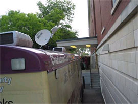 Bookmobile in front of library with dish opened
